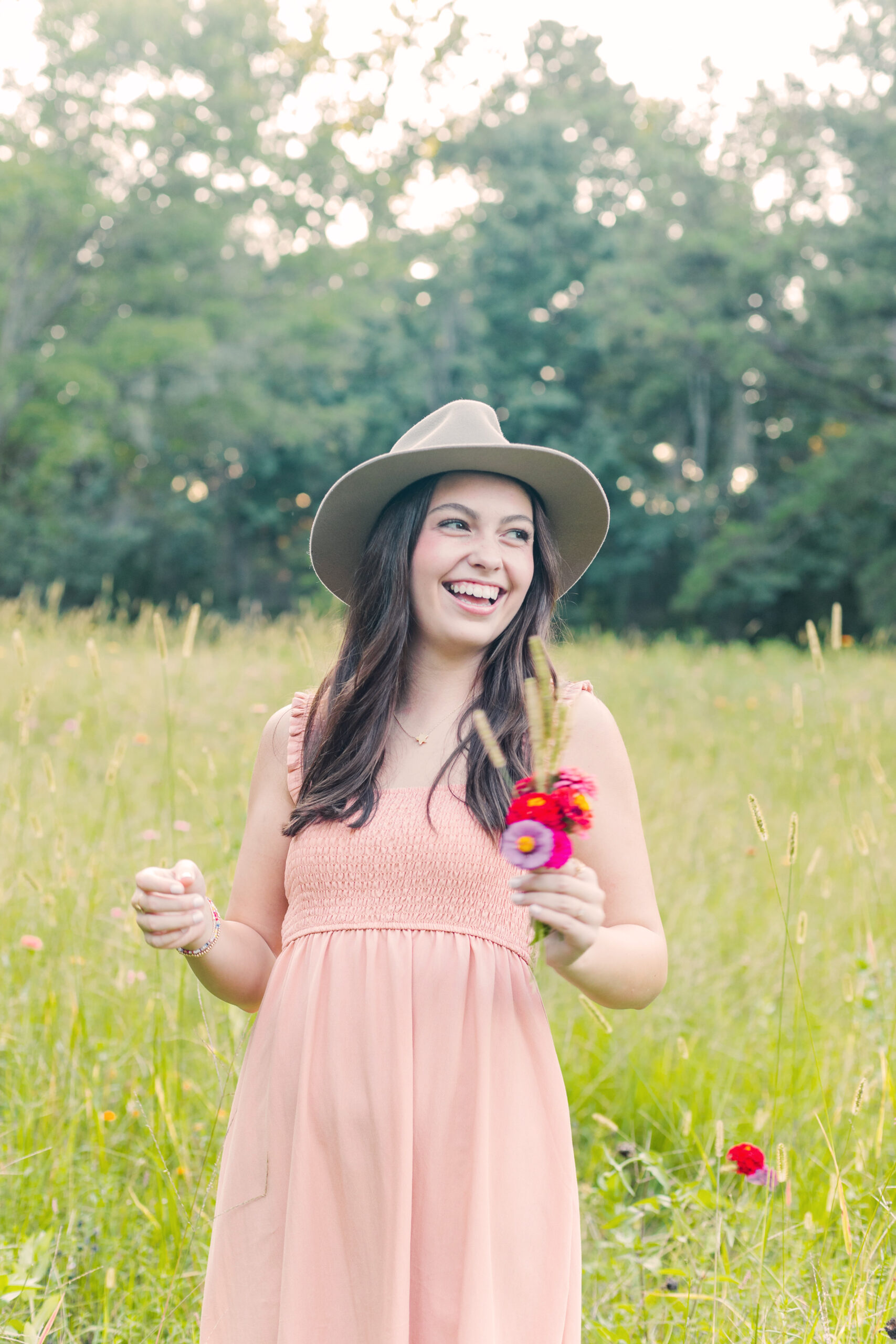 High School Senior girl laughing in a field of flowers for senior portraits