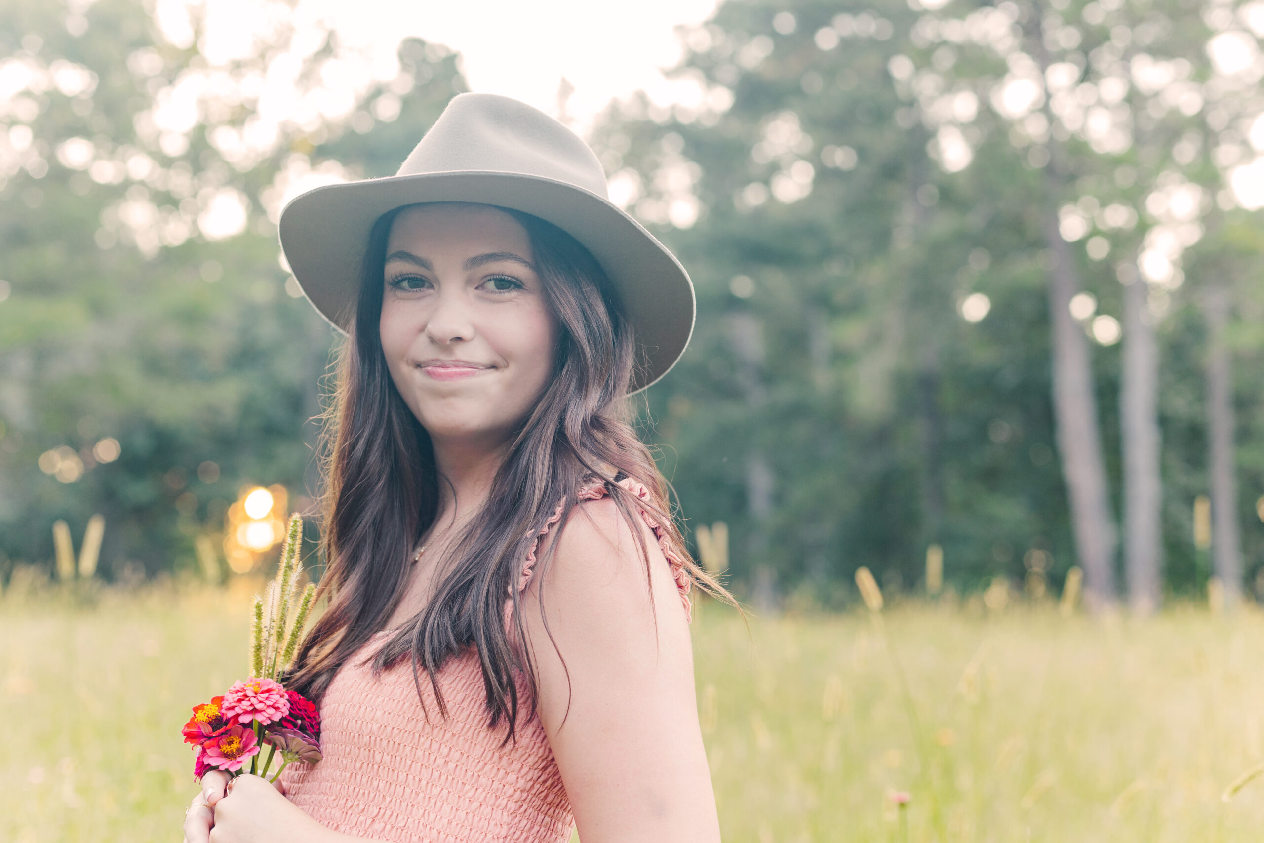 High School Senior girl in a field holding flowers