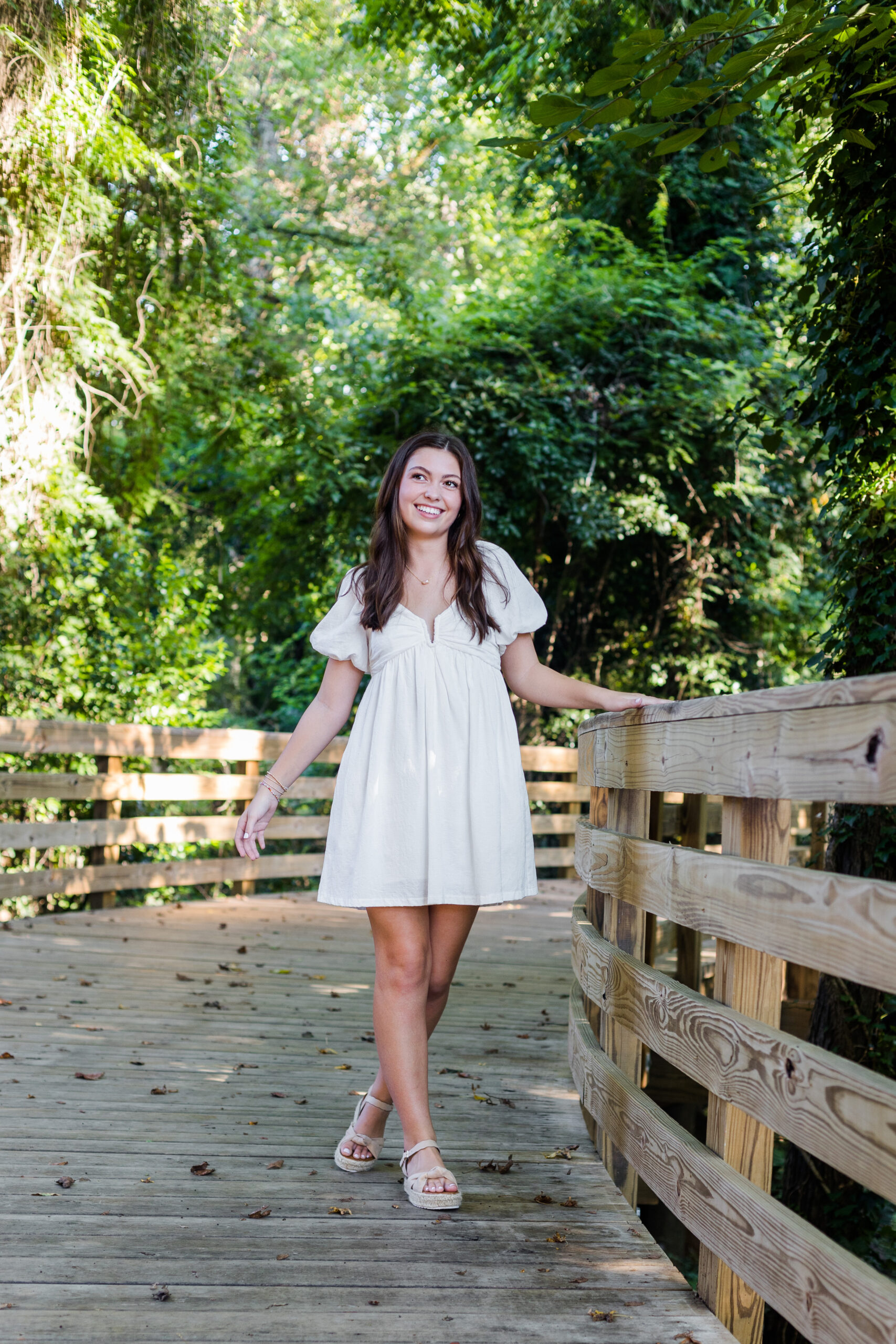 High School Senior girl walking on a bridge surrounded by greenery