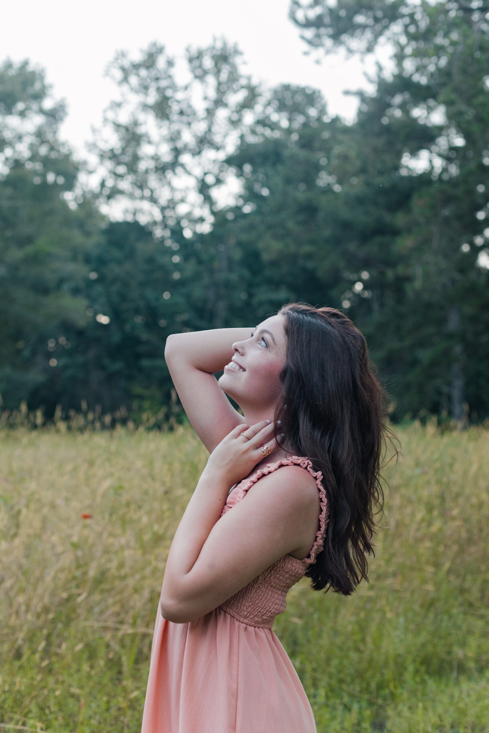 High school senior girl in a field playing with her hair for senior portraits