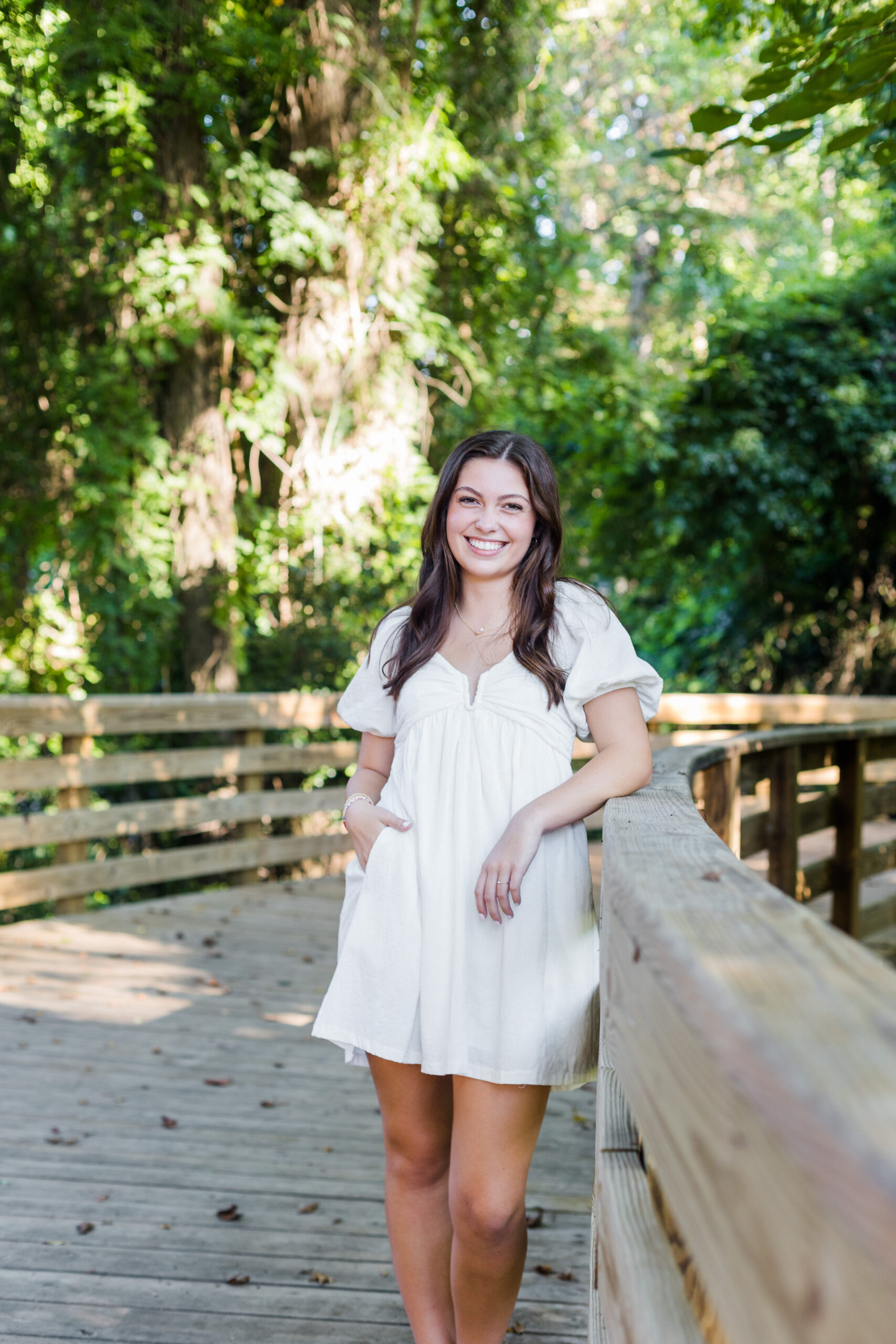 High School senior girl posing o a bridge with a big smile