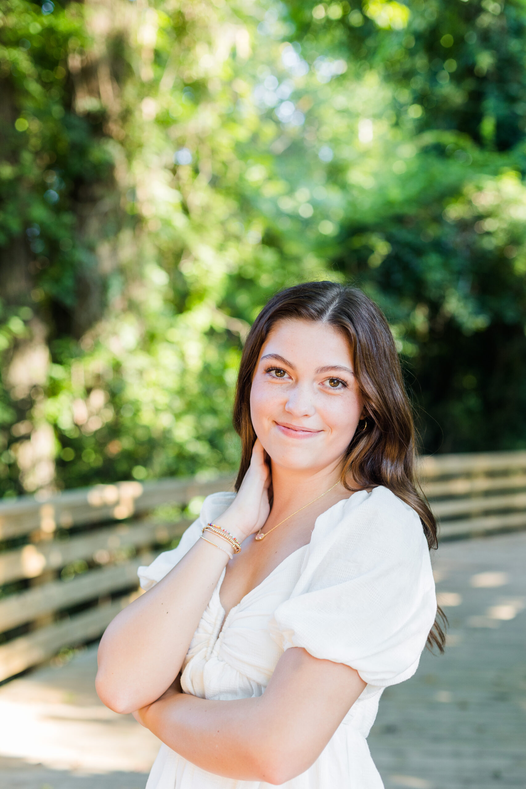 High school senior girl posing for senior portraits on a bridge with her hand near her face