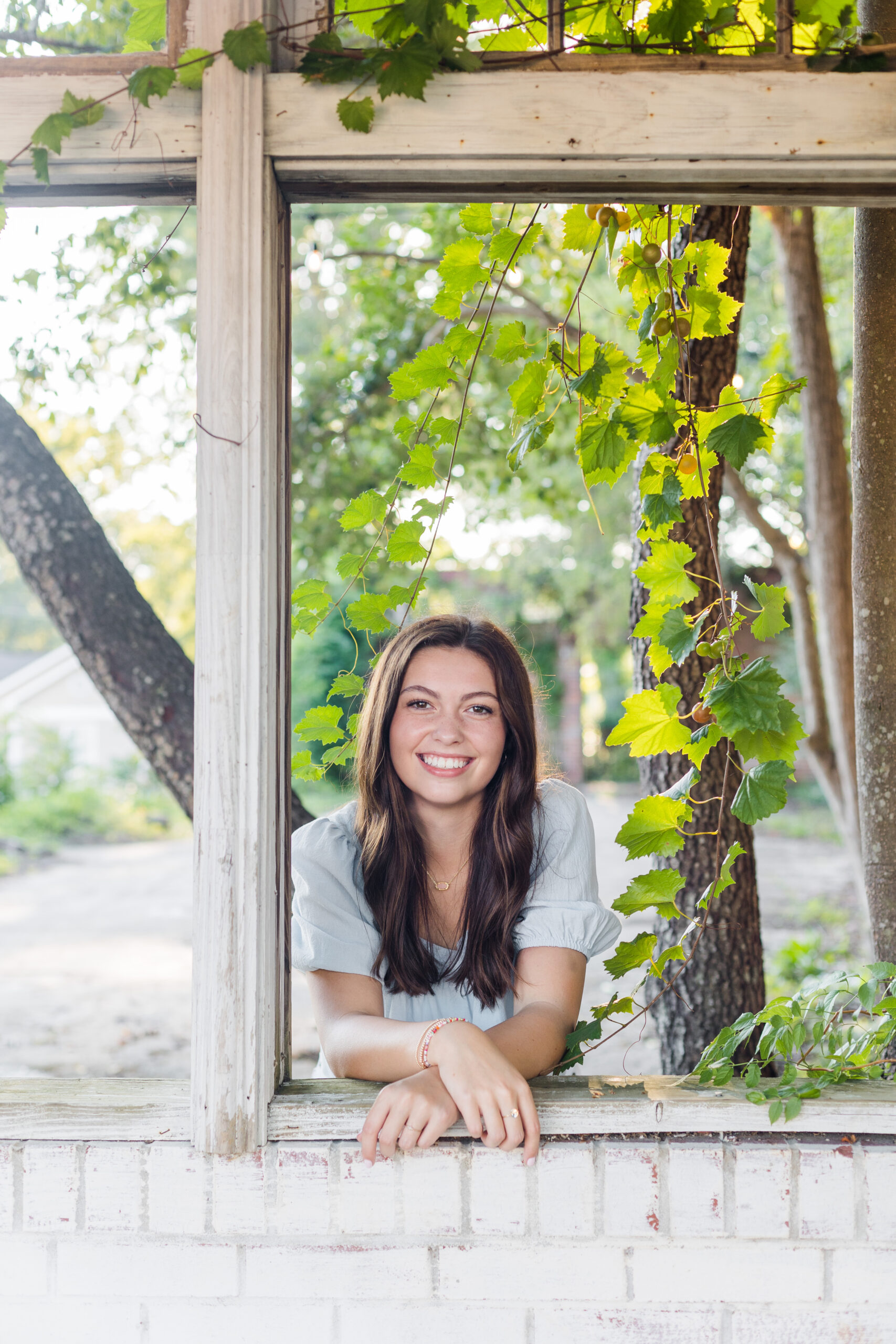 High School Senior girl looking out window of abandoned building for senior portraits